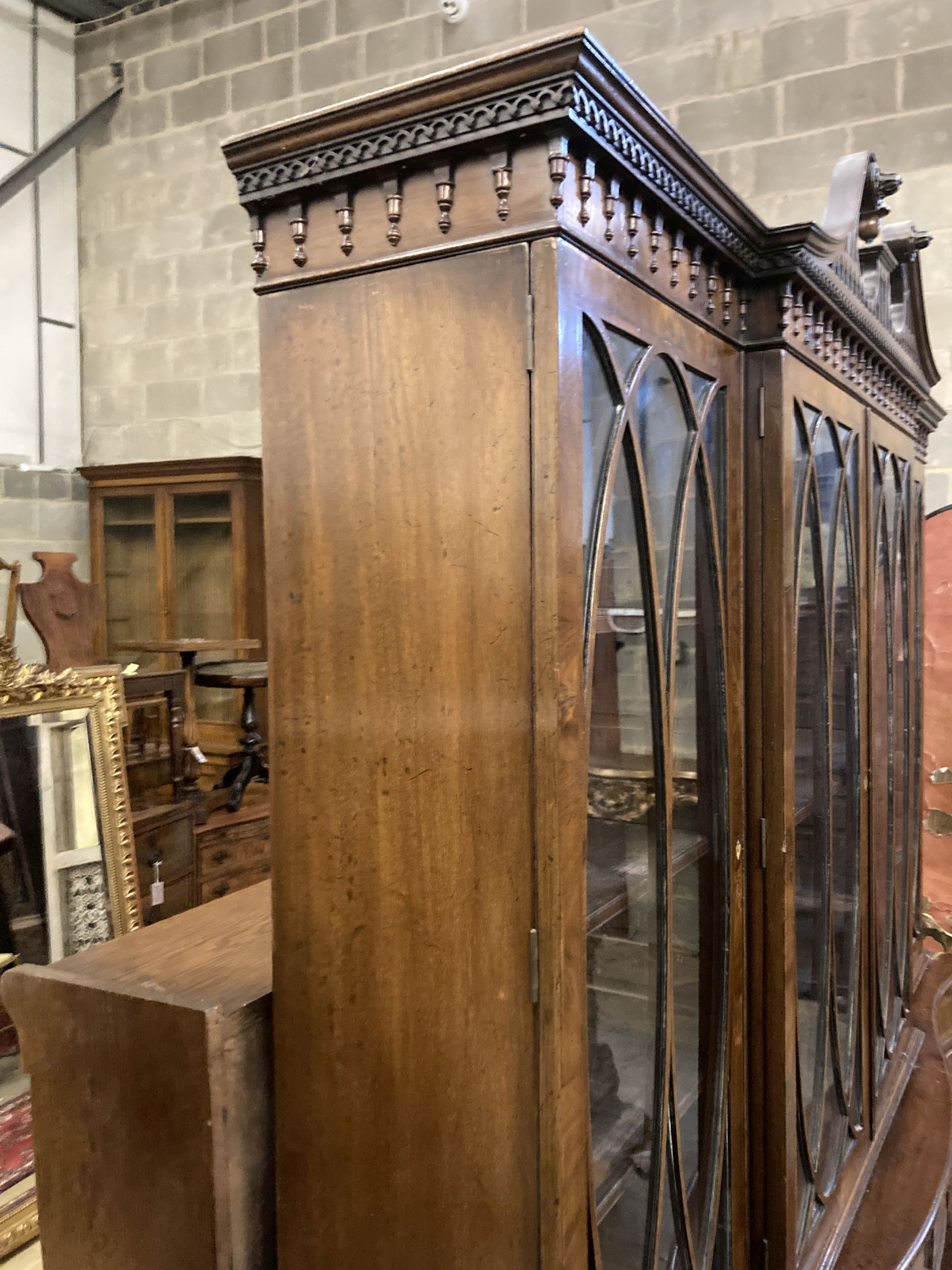 A George III style mahogany and walnut banded breakfront bookcase, with pierced broken swan neck pediment over oval glazing bars,